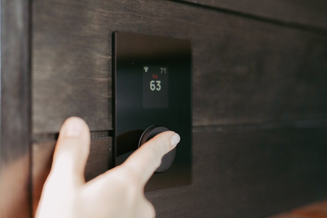 Hand adjusting a smart thermostat on the wall